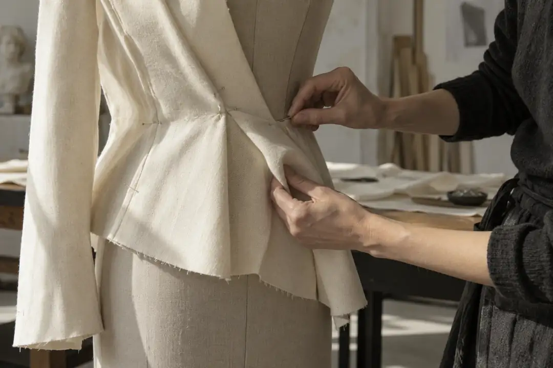 Imagen de inspiración: manos trabajando una toile de chaqueta en un maniquí.
